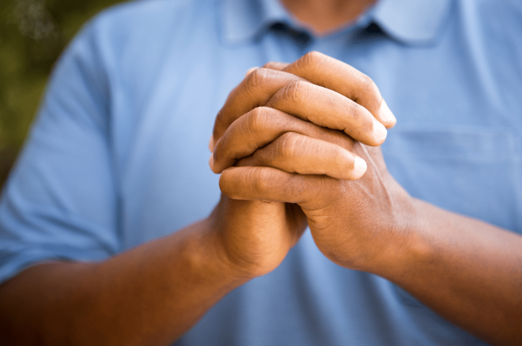 A close-up image of a person's hands clasped together, conveying a sense of prayer or reflection.